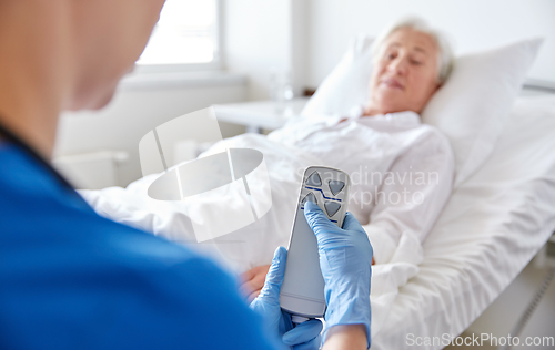 Image of nurse adjusting bed for senior woman at hospital