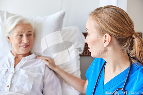 Image of doctor or nurse visiting senior woman at hospital