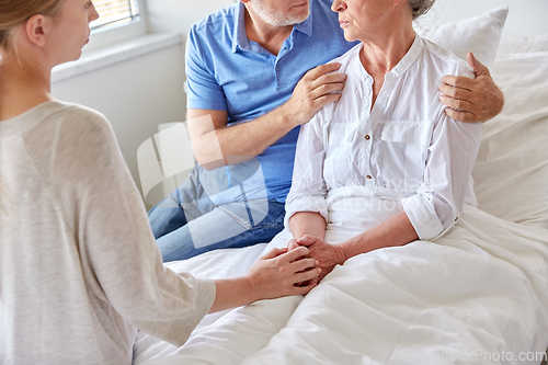 Image of family visiting senior woman at hospital