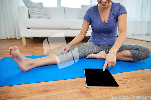 Image of woman with tablet pc computer doing yoga at home