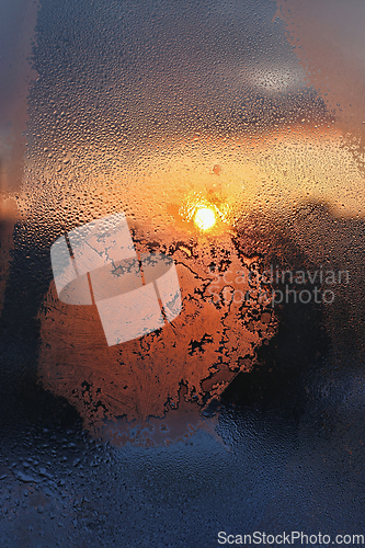 Image of Ice patterns, water drops and sunlight on a winter window glasss