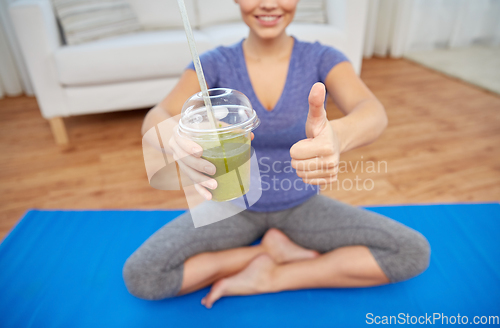 Image of happy woman with cup of smoothie showing thumbs up