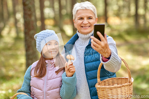 Image of grandma with granddaughter taking selfie in forest