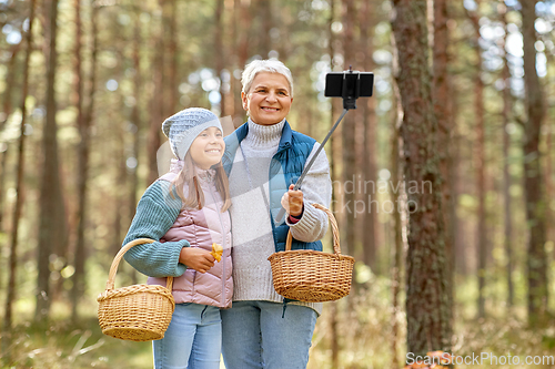 Image of grandma with granddaughter taking selfie in forest