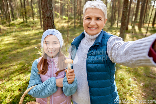 Image of grandma with granddaughter taking selfie in forest