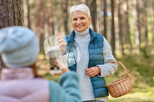 Image of granddaughter photographing grandma with mushrooms