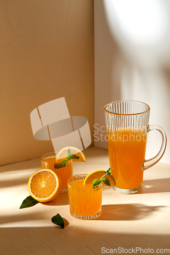 Image of glasses with orange juice and peppermint on table