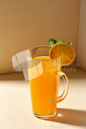 Image of jug with orange juice and peppermint on table