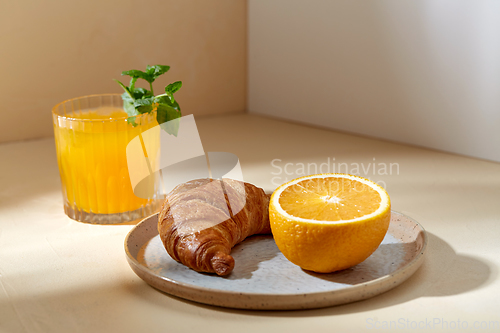 Image of glass of orange juice and croissant on plate