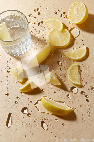 Image of glass of water and lemon slices on wet table