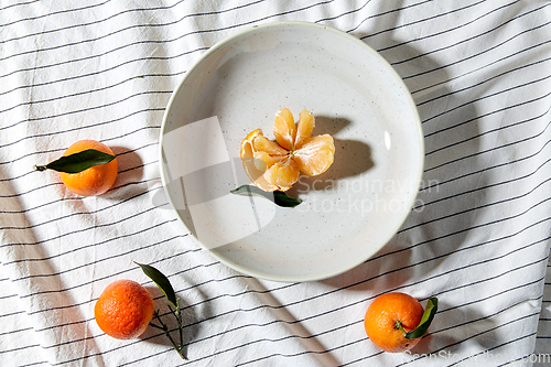 Image of still life with mandarins on plate over drapery