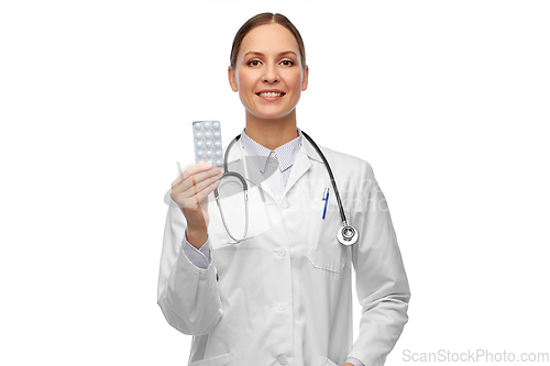 Image of smiling female doctor holding medicine pills