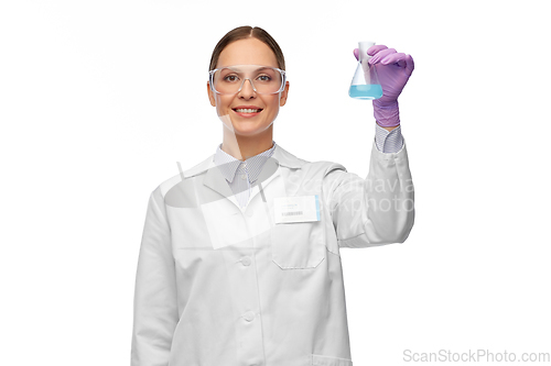 Image of female scientist in goggles with chemical in flask