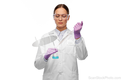 Image of female scientist in goggles with chemical in flask