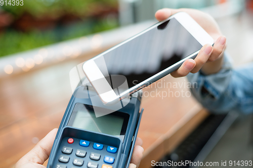 Image of Woman using cellphone for payment by NFC technology