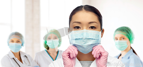 Image of asian female doctor in medical mask and gloves