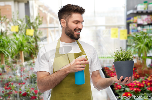 Image of happy male gardener moisturizing flower at shop