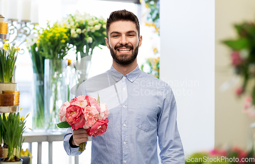 Image of happy smiling man with peonies at flower shop