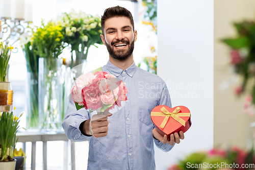 Image of happy man with flowers and valentine's day gift