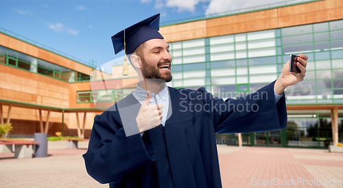 Image of male graduate student with smartphone takes selfie