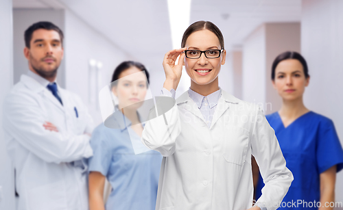 Image of smiling female doctor with colleagues at hospital