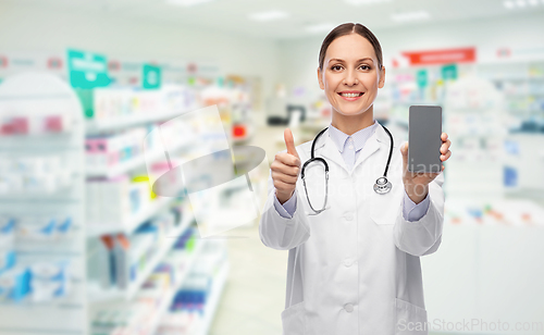 Image of doctor with smartphone shows thumbs up at pharmacy