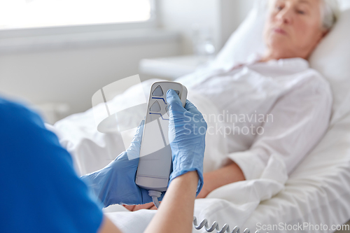 Image of nurse adjusting bed for senior woman at hospital