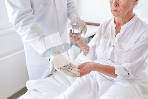 Image of doctor giving medicine to senior woman at hospital