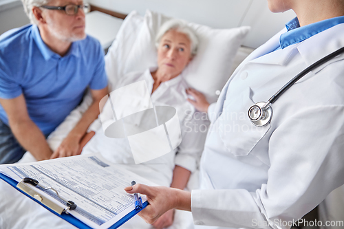 Image of old couple and doctor with clipboard at hospital