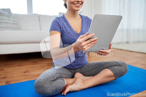 Image of woman with tablet pc computer doing yoga at home