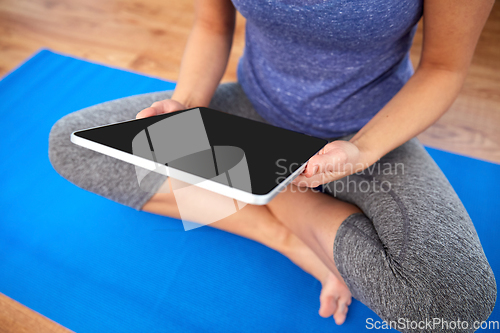 Image of woman with tablet pc computer doing yoga at home