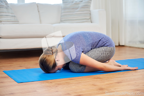 Image of woman doing yoga child pose at home