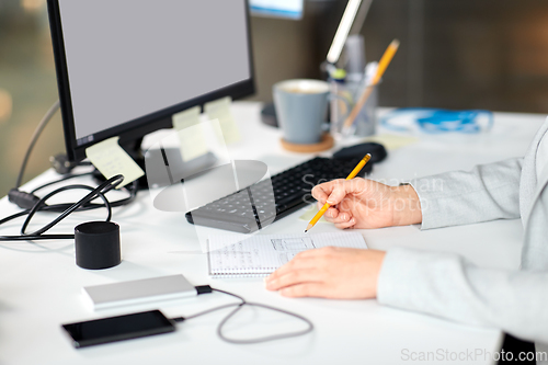 Image of businesswoman with notebook and computer at office