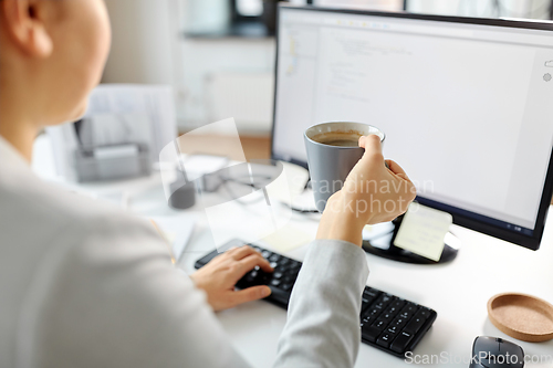 Image of businesswoman with computer and coffee at office