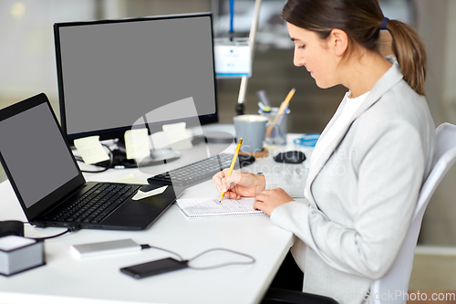 Image of businesswoman with notebook and laptop at office