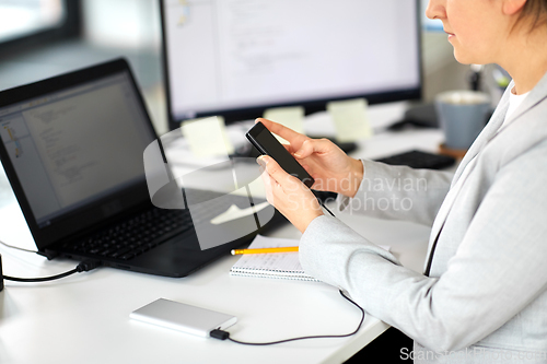 Image of businesswoman with smartphone working at office