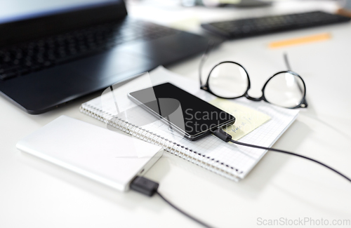 Image of smartphone with powerbank on table at office