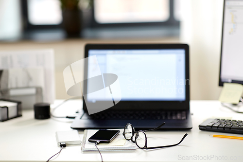 Image of laptop, smartphone and notebook on table at office