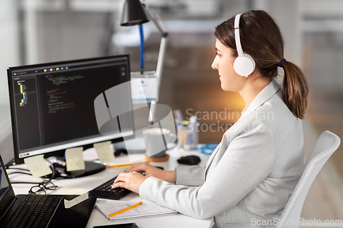 Image of programmer in headphones with computer at office