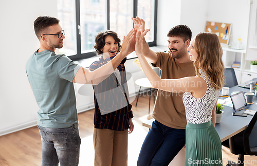 Image of happy business team making high five at office