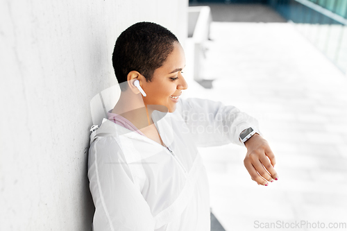 Image of african woman with earphones and smart watch