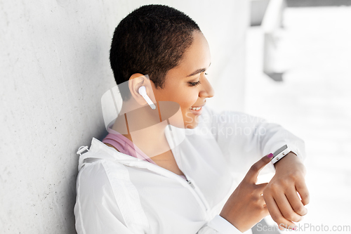 Image of african woman with earphones and smart watch