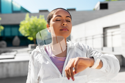 Image of young woman with smart watch breathing outdoors