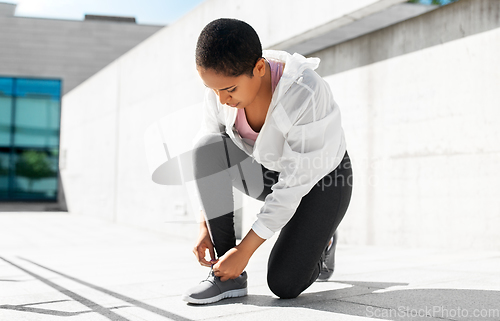 Image of african american woman tightening sneakers