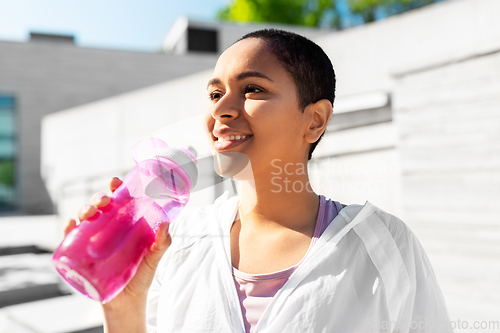 Image of african american woman drinking water from bottle