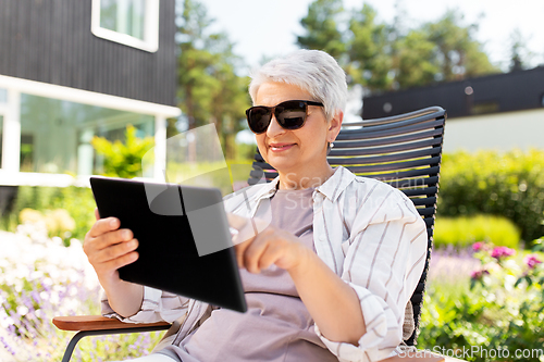 Image of happy senior woman with tablet pc at summer garden