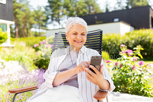 Image of happy senior woman with phone at summer garden