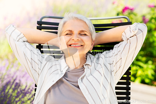 Image of happy senior woman resting at summer garden