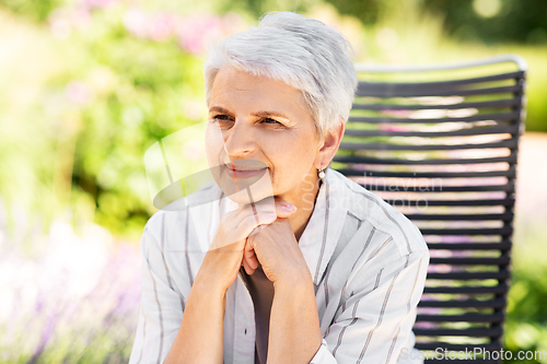 Image of happy senior woman resting at summer garden