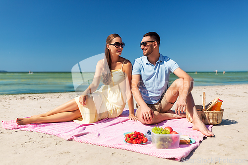 Image of happy couple having picnic on summer beach